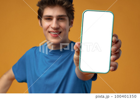 Young delivery man showing smartphone with blank screen in studio Young delivery man showing smartphone with blank screen in studio 100401350
