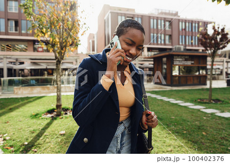Female african student talking on the phone near the university campus 100402376