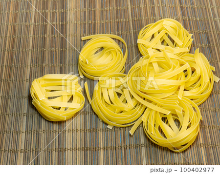 Pasta nests on a wicker background. Type of noodle. Culinary background. Cooking. 100402977