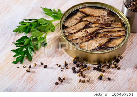 Tinned small smoked sardines on background with greens 100405251