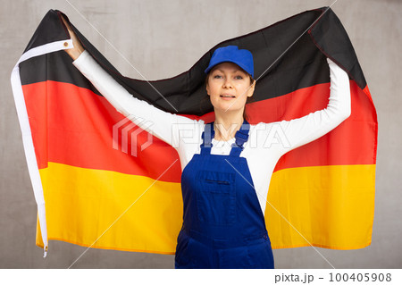 Cheerful female worker with wide grin on her face holding flag of germany 100405908