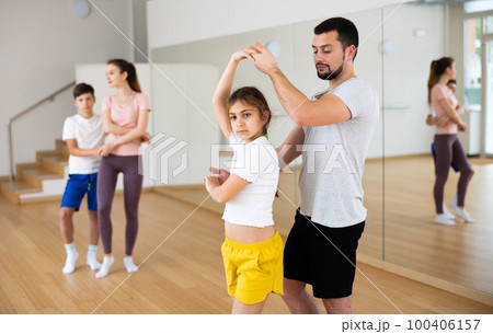 Teen girl practicing boogie-woogie in pair with father in dance studio 100406157