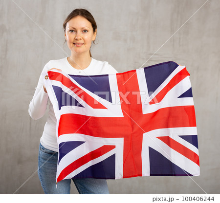 Happy woman posing with flag of United Kingdom in studio 100406244