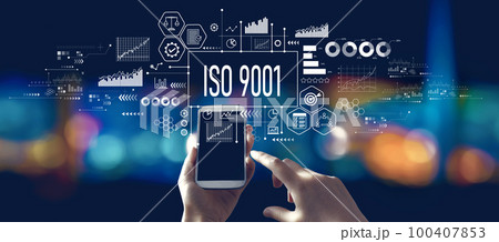 ISO 9001 theme with person using a smartphone at night 100407853