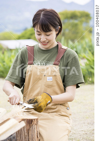 焚き火用にフェザースティックを作る若い女性　ソロキャンプイメージ 100408037