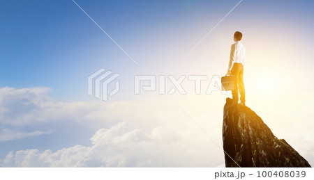 Back view of young man in suit standing on mountain top. 100408039