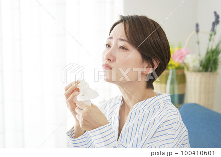 リビングで鼻炎に悩む女性 100410601