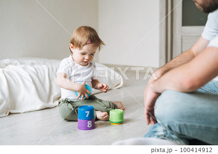Happy father and baby girl little daughter having fun playing with toy in children room at home Happy father and baby girl little daughter having fun playing with toy in children room at home 100414912
