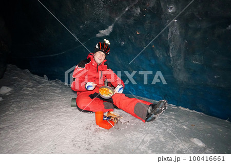 A mountaineer caver eats in a deep ice cave A mountaineer caver eats in a deep ice cave 100416661