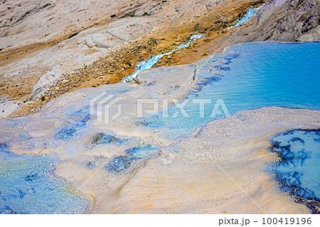 View of natural terraces in Pamukkale on a summer day. Close-up texture of limestone and water flowing over it. 100419196