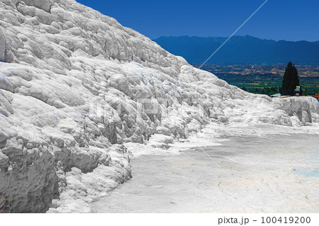 View of natural travertine pools and terraces in Pamukkale on a summer day. Texture of a white wall close-up View of natural travertine pools and terraces in Pamukkale on a summer day. Texture of a white wall close-up 100419200