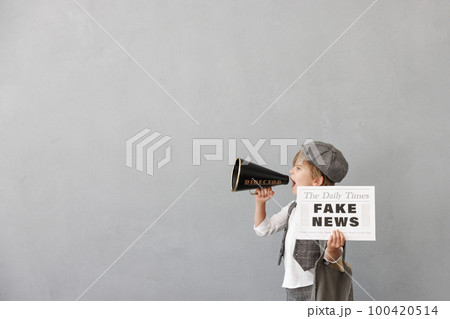 Newsboy shouting against grunge wall background. Boy selling fake news 100420514