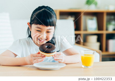 ドーナツを食べる小学生の女の子 100422353