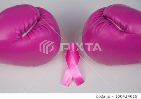 Pink boxing gloves and pink ribbon on a white background. The concept of the fight against breast cancer. Pink boxing gloves and pink ribbon on a white background. The concept of the fight against breast cancer. 100424019