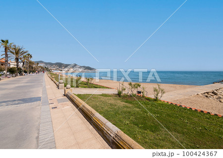 Fascinating view of the promenade on the backdrop of the sea and mountains and palm trees on sunny warm summer day. Concept of beach area in tourist city during a holiday. Copyspace 100424367