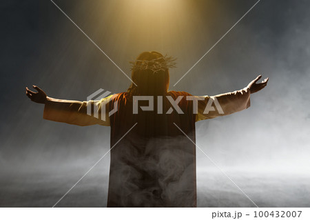 Rear view of Jesus Christ with a crown of thorns raised hands and praying to god 100432007