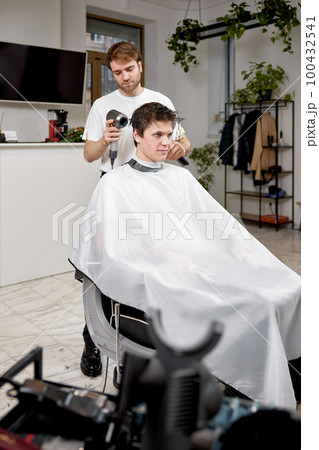 Professional hairdresser during work with man client with hair dryer 100432541
