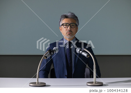 記者会見風のグレイヘアの男性　 100434128