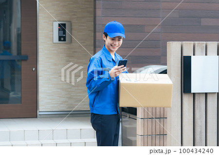 段ボールを持ってスマホを使う作業員　宅配便　デリバリースタッフ 100434240
