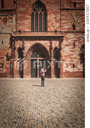 Vertical shot of a tourist shooting the Basel Minster Cathedral in Basel, Switzerland Vertical shot of a tourist shooting the Basel Minster Cathedral in Basel, Switzerland 100437807