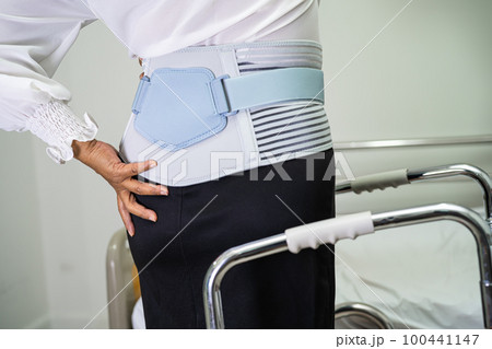 Asian lady patient wearing back pain support belt for orthopedic lumbar with walker. Asian lady patient wearing back pain support belt for orthopedic lumbar with walker. 100441147