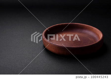 Empty brown colored ceramic plate on dark concrete background 100445243