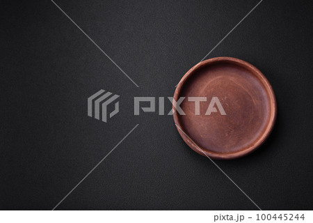 Empty brown colored ceramic plate on dark concrete background 100445244