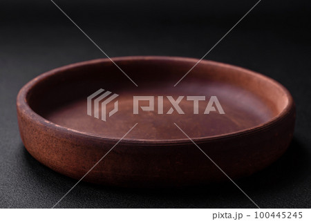 Empty brown colored ceramic plate on dark concrete background Empty brown colored ceramic plate on dark concrete background 100445245