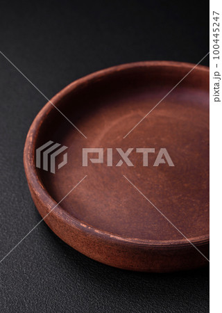 Empty brown colored ceramic plate on dark concrete background Empty brown colored ceramic plate on dark concrete background 100445247