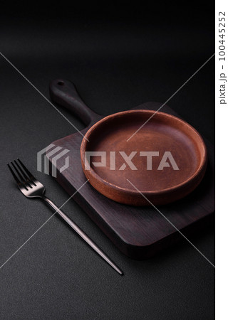 Empty brown colored ceramic plate on dark concrete background Empty brown colored ceramic plate on dark concrete background 100445252
