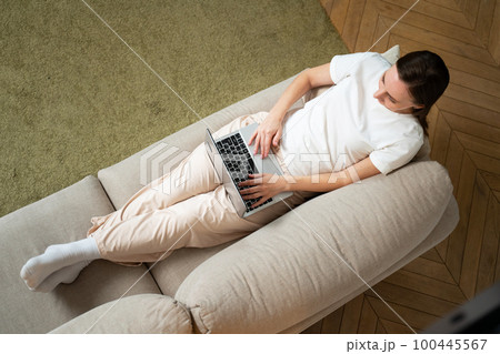 Top view of a young woman using her tablet while relaxing on the couch 100445567
