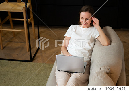 Top view of a young woman using her tablet while relaxing on the couch Top view of a young woman using her tablet while relaxing on the couch 100445991
