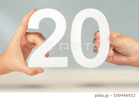 Number twenty in hand. Hand holding white number 20 on blurred background with copy space. Concept with number twenty. 20 percent, birthday 20 years Number twenty in hand. Hand holding white number 20 on blurred background with copy space. Concept with number twenty. 20 percent, birthday 20 years 100446932