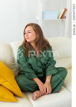 Cute female model in pajama enjoying morning. Pleasant woman sitting on sofa. Good mood 100447007