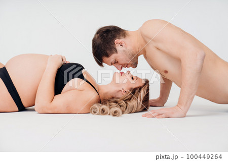 a loving and passionate man and pregnan woman in black underwear on the floor a loving and passionate man and pregnan woman in black underwear on the floor 100449264