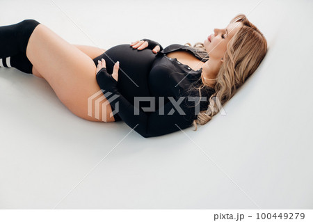 profile a beautiful pregnant in a black bodysuit lies on a cyclorama profile a beautiful pregnant in a black bodysuit lies on a cyclorama 100449279
