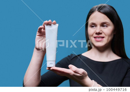 Close-up of white clean tube with cosmetic product in hands of woman 100449716
