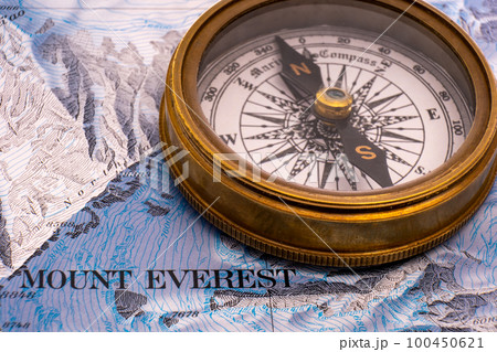Close up of vintage brass compass on map detail of Mt. Everest topographical map showing contour lines, elevation. High quality photo 100450621