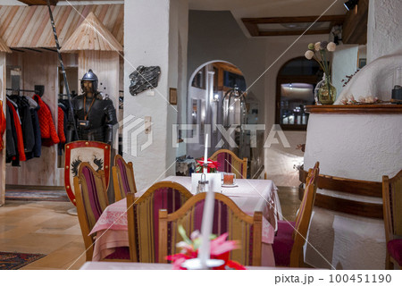 Empty wooden chairs arranged around table with candle in center with male sculpture in the background at alpine luxurious hotel Empty wooden chairs arranged around table with candle in center with male sculpture in the background at alpine luxurious hotel 100451190