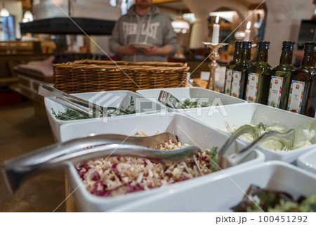 Closeup of white containers with various food and serving tongs arranged on counter at luxury hotel during buffet Closeup of white containers with various food and serving tongs arranged on counter at luxury hotel during buffet 100451292