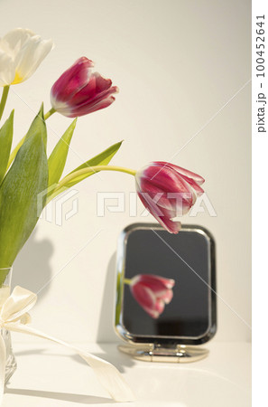 Reflection of a red tulip flower in a mirror, on a white table. Reflection of a red tulip flower in a mirror, on a white table. 100452641