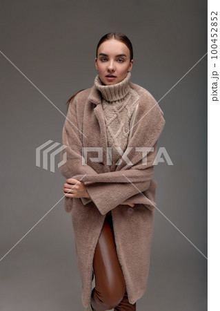 Fashion young woman in a faux fur coat on a gray background. 100452852
