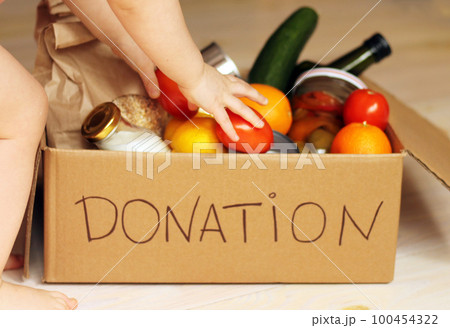 Girl putting food in a donation box 100454322