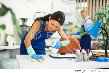 Asian female cleaning desk in office 100457853