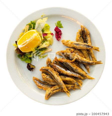 Deep fried anchovies with vegetable garnish and fresh lemon 100457943