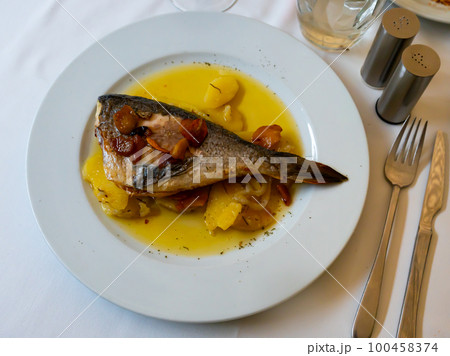 Grilled dorada fish with potatoes stewed in gravy 100458374