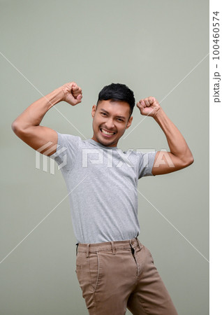 Happy Asian man raising hand up, rejoicing, dancing with joy, yes gesture, winning 100460574