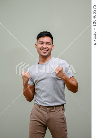 Happy Asian man raising hands up, rejoicing, yes gesture, winning, victory, celebrating 100460575