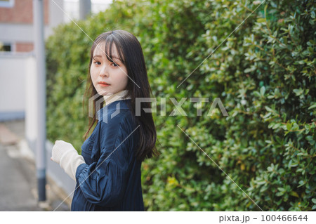 緑の植木の前を歩く女の子 緑の植木の前を歩く女の子 100466644