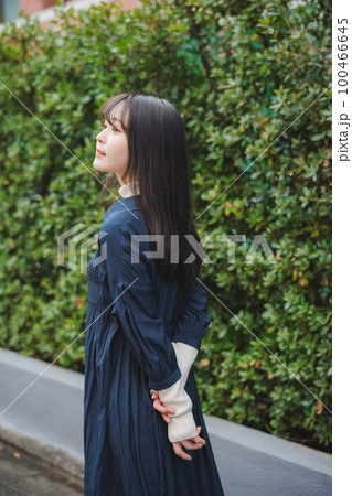 緑の植木の前を歩く女の子 100466645